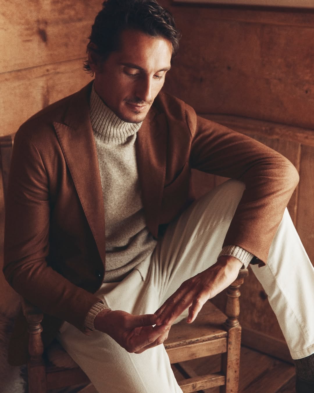 uomo con giacca marrone, maglione e pantaloni beige